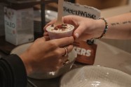 A parfait cup topped with granola and dried fruit being handed across the counter